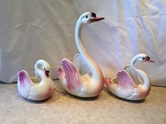 three ceramic swan figurines sitting next to each other