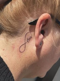 a woman with a small tattoo on her left side behind the ear that says love