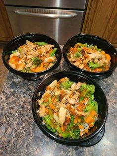 three black bowls filled with food on top of a counter