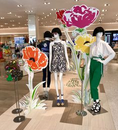 three mannequins are dressed up with flowers in front of them on display