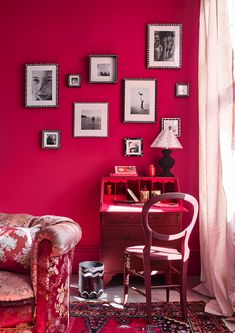 a living room with pink walls and pictures on the wall, including a red chair