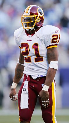 a football player is standing on the field with his hand in his pocket and wearing a helmet