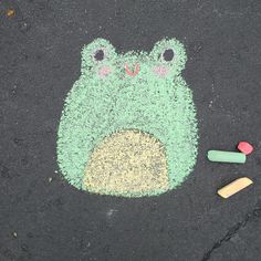 a drawing of a frog on the ground with crayons and colored chalks