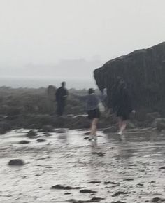 three people walking on the beach in the rain