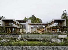 a large modern house in the middle of a lush green area with lots of trees