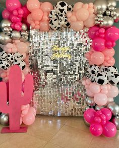 a pink and silver balloon arch with balloons on it in front of a mirror wall