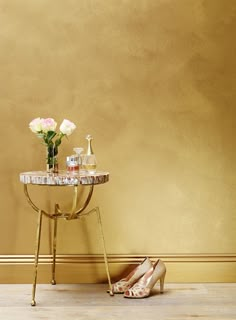 a pair of high heeled shoes sitting next to a table with flowers on it