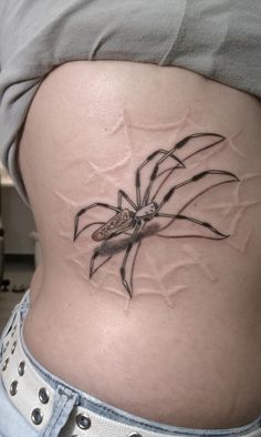 a woman's stomach with a spider tattoo on it