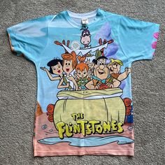 All Over Print Screen Printed Flintstones T Shirt. Never Worn And No Flaws. It’s A Slim Fit Size M So You Can Use It If You’re A Size Small As Well. Ships From A Smoke Free Dog Friendly Home Fun Short Sleeve Tops With All Over Print, Relaxed Fit Graphic Tee With Cartoon Print, Fun Blue Tops With Sublimation Print, Fun Blue Top With Sublimation Print, Blue All Over Print Sublimation Short Sleeve, Cotton Graphic Tee With Cartoon Print, Fred Flinstone Shirt, Cartoon Print Short Sleeve T-shirt, Disney Cotton T-shirt With Cartoon Print