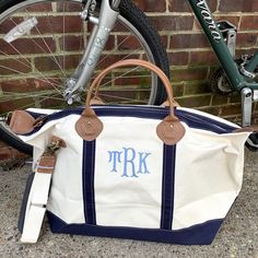 a white and blue tote bag sitting next to a bicycle on the sidewalk with initials