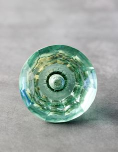 a green glass object sitting on top of a gray table next to a white wall