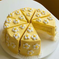 a white cake with yellow frosting and flowers on it's side, cut in half