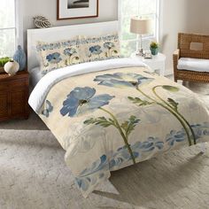 a bed with blue flowers on it in a room next to a window and chair