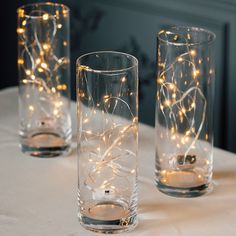 three glasses with lights in them sitting on a table