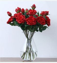 a vase filled with red roses on top of a table