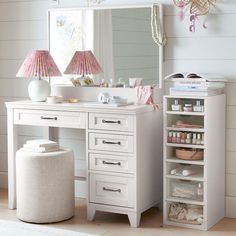 a white dressing table with drawers and a large mirror on the wall next to it