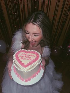 a woman holding a heart shaped cake in front of her face