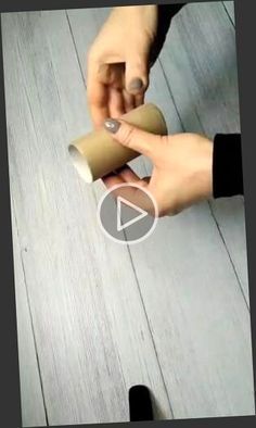 two hands holding coffee cups on top of a wooden floor next to black and white objects