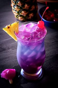 a purple drink with a pineapple on the rim and a cherry garnish