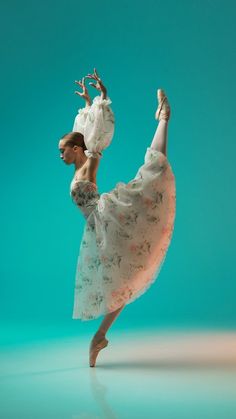 a woman in a white dress is dancing with her arms stretched out and legs bent