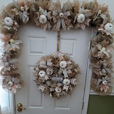 a wreath on the front door with flowers and burlucks hanging from it