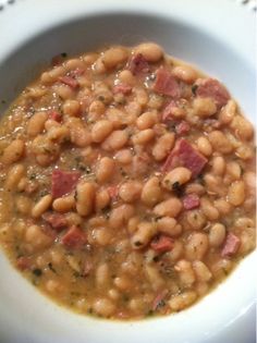 a white bowl filled with beans and ham