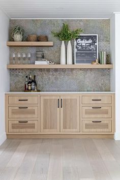 a kitchen with wooden cabinets and shelves filled with bottles, wine glasses and other items