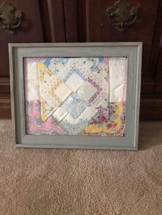 an old picture frame is decorated with quilts and other fabric items in the shape of a square