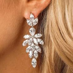 a close up view of a woman's ear wearing earrings with crystal stones on them