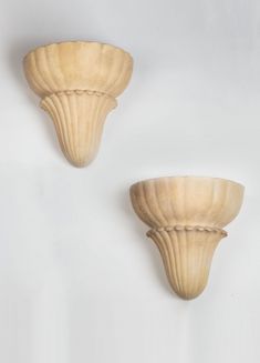 two wooden scallops are shown against a white wall, one is shaped like a shell