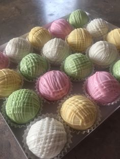 a box filled with different colored cupcakes on top of a table