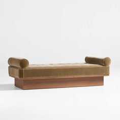 a brown couch sitting on top of a wooden platform next to a white wall and floor