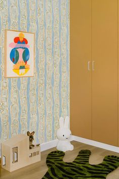 a child's room decorated in pastel colors and striped wallpaper, with a toy rabbit on the floor