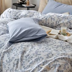 an unmade bed with blue and white comforters, pillows and blankets on it