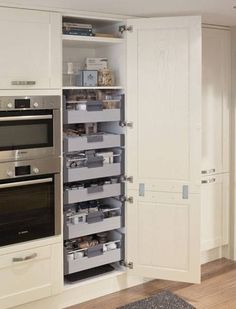 a kitchen with white cabinets and drawers filled with silver items in the cupboards next to an oven