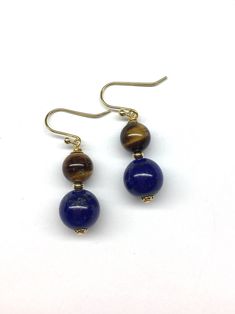 This pair of earrings are made with deep blue lapis lazuli beads and tiger eye beads. - Made with genuine lapis lazuli beads, genuine tiger eye beads, copper beads, copper wires and gold-plated sterling silver hooks - Approximately 35 mm / 1.38 inches in length - Approximately 8 mm diameter of tiger eye bead and 10 mm diameter of lapis lazuli bead Visit my shop for more: http://www.etsy.com/ca/shop/RitaCollection If you have any questions regarding the item or my store in general, feel free to m Blue Round Beads Pierced Earrings, Blue Pierced Earrings With Round Beads, Spiritual Hypoallergenic Round Beads Earrings, Hypoallergenic Spiritual Round Bead Earrings, Blue Round Beads Spiritual Earrings, Blue Spiritual Earrings With Round Beads, Blue Spiritual Dangle Earrings, Spiritual Blue Dangle Earrings, Ornament Inspiration