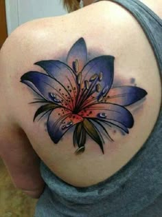 a woman's back with a blue flower tattoo on it