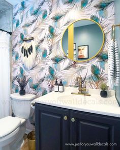 a bathroom decorated in blue and white with peacock feathers on the wall behind the toilet