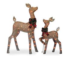 two lighted deer statues with bows and lights on their heads, standing next to each other