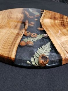 a glass plate with some wood and leaves on it's side, sitting on a black surface