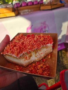 a piece of cake that is sitting in a paper container on a table with other food items