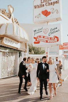 a bride and groom are walking down the street in front of a white chapel sign