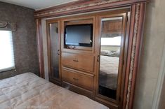 a bedroom with a bed, dresser and television in it