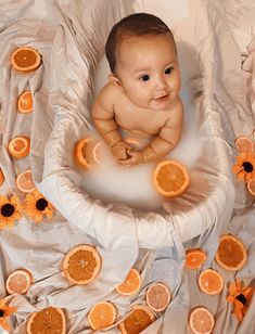 a baby in a bath surrounded by orange slices