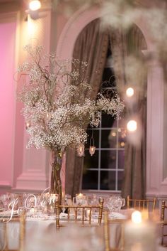 the table is set with white flowers and candles for an elegant wedding reception in front of a large window