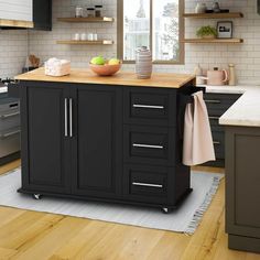 a kitchen island with a bowl of fruit on top of it in the middle of a wooden floor