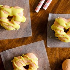 four doughnuts with yellow icing sitting on wax paper