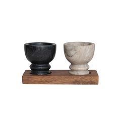 two black and white bowls sitting on top of a wooden stand