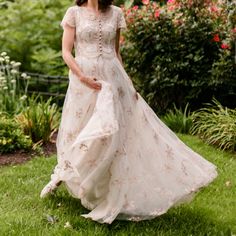 a woman in a white dress is walking through the grass