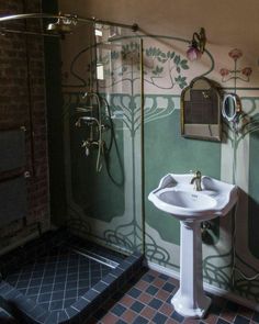 a bathroom with a sink, mirror and shower stall in the corner is decorated with floral wallpaper